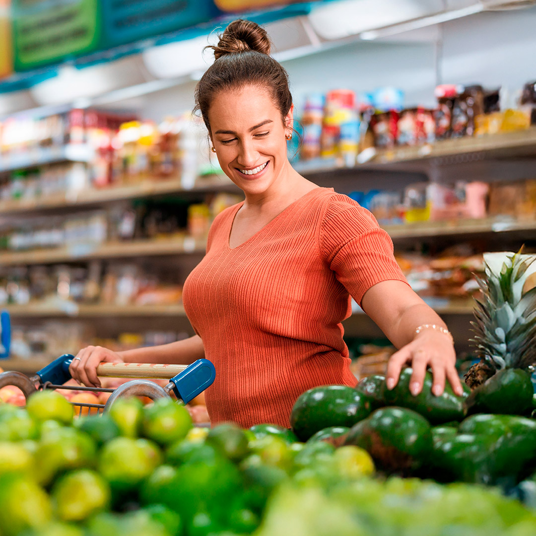 Cliente feliz seleccionando frutas como el aguacate | Global Green Gourmet